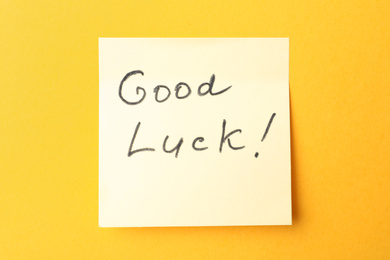 Note with phrase GOOD LUCK on orange background, top view