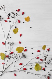 Photo of Flat lay composition with branches, autumn leaves and berries on white wooden table