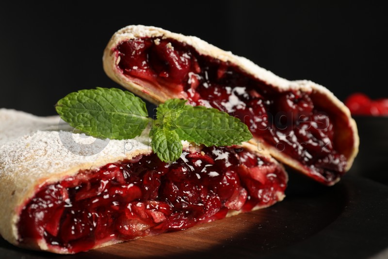Photo of Delicious strudel with cherries, powdered sugar and mint on table, closeup
