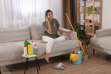 Young mother talking on phone in messy living room