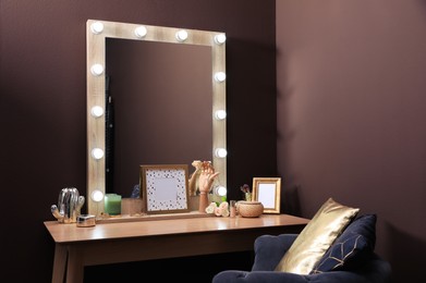 Stylish dressing table with mirror near brown wall in room