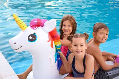 Happy children on inflatable unicorn in swimming pool