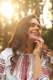 Beautiful woman in embroidered shirt outdoors on sunny day. Ukrainian national clothes