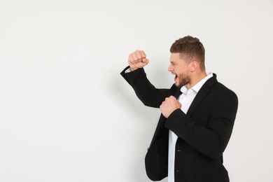Young man ready to fight on white background, space for text