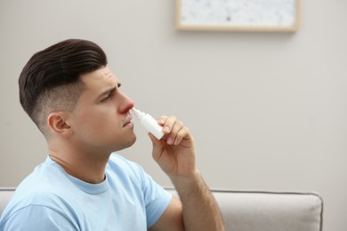 Ill man using nasal spray at home