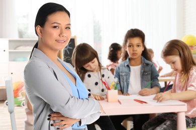 Happy Asian woman in classroom with children
