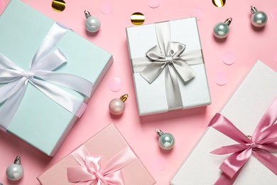 Photo of Beautiful gift boxes, Christmas balls and confetti on pink background, flat lay