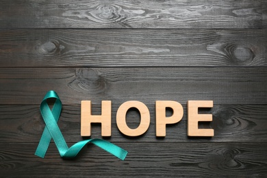 Word Hope made of letters and teal awareness ribbon on wooden background, top view. Symbol of social and medical issues