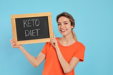 Woman holding blackboard with phrase Keto Diet on light blue background