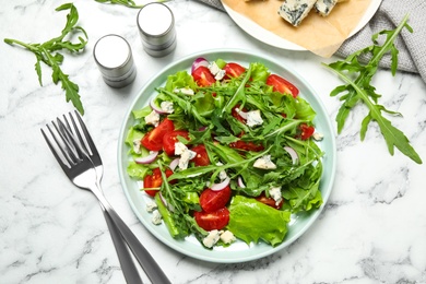 Delicious salad with arugula and tomatoes on white marble table, flat lay