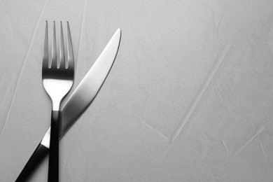 Photo of Fork and knife on grey table, flat lay. Space for text