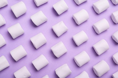 Delicious puffy marshmallows on lilac background, flat lay