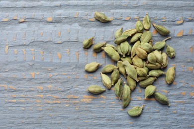 Pile of dry cardamom pods on grey wooden table, top view. Space for text