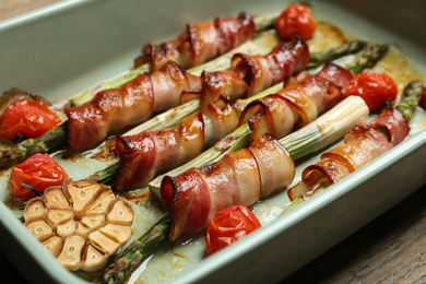 Oven baked asparagus wrapped with bacon in ceramic dish, closeup