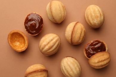 Photo of Homemade walnut shaped cookies with boiled condensed milk on pale brown background, flat lay