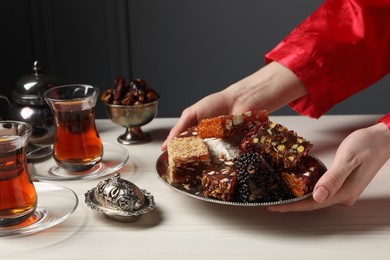 Photo of Woman serving Turkish delight on vintage tray, closeup