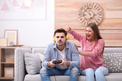 Young woman trying to draw attention of her man playing video games at home