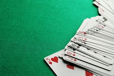 Photo of Deck of playing cards on green table, closeup. Space for text