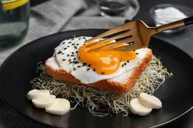 Tasty toast served with egg, cheese and microgreens on black plate, closeup