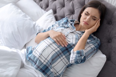 Young pregnant woman suffering from headache at home