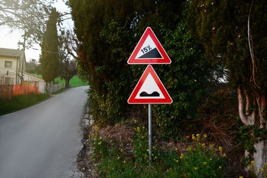 Traffic signs STEEP HILL UPWARDS and UNEVEN ROAD outdoors