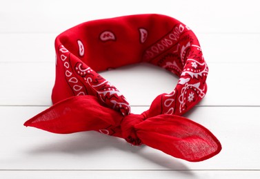 Tied red bandana with paisley pattern on white wooden table