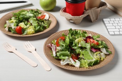 Photo of Plates of fresh salad and cutlery on white wooden table. Business lunch
