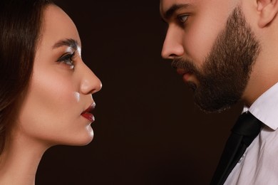 Handsome bearded man and sexy lady on dark brown background, closeup