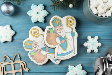 Delicious gingerbread cookies on blue wooden table, flat lay. St. Nicholas Day celebration