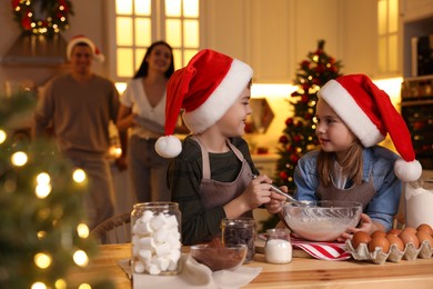 Cute little children making dough for delicious Christmas cookies at home