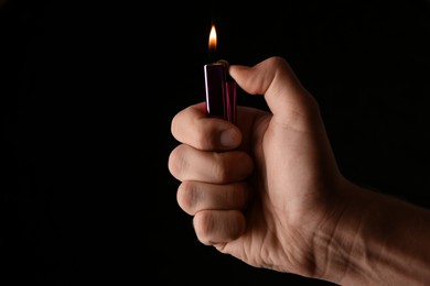 Man holding lighter on black background, closeup. Space for text