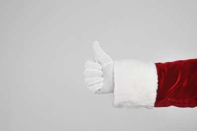 Santa Claus showing thumb up on light grey background, closeup of hand