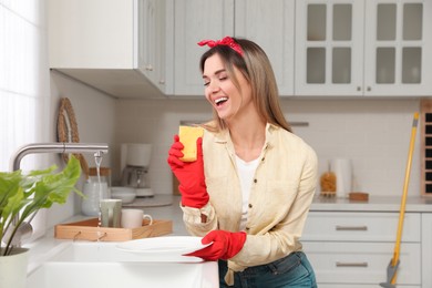 Woman singing while washing dishes in kitchen
