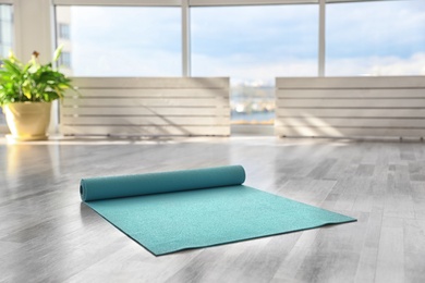 Unrolled light blue yoga mat on floor in room