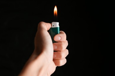 Woman holding green lighter on black background, closeup