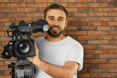 Operator with professional video camera near brick wall