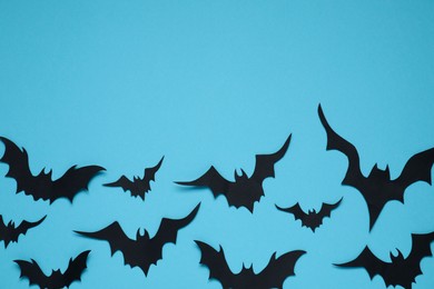 Flat lay composition with paper bats on light blue background, space for text. Halloween decor