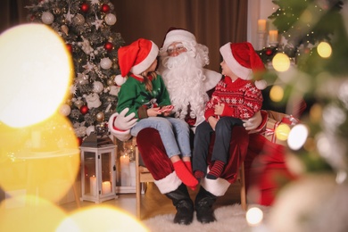Santa Claus and children in room decorated for Christmas