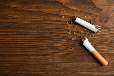 Photo of Broken cigarette on wooden table, flat lay with space for text. Quitting smoking concept