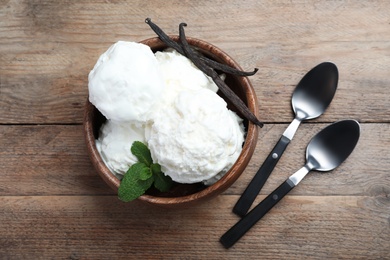 Photo of Yummy vanilla ice cream served on wooden table, flat lay