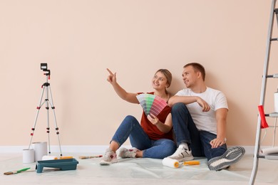 Couple with paint chips discussing new wall color in apartment during repair, space for text