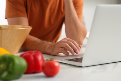 Man making dinner while watching online cooking course via laptop in kitchen, closeup