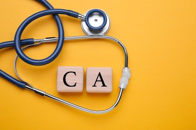 Photo of Stethoscope and calcium symbol made of wooden cubes with letters on orange background, flat lay. Space for text