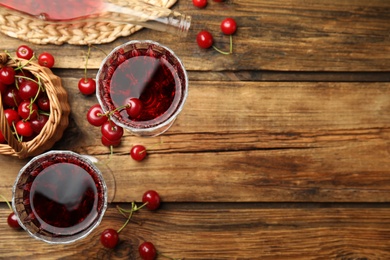 Delicious cherry wine with ripe juicy berries on wooden table, flat lay. Space for text