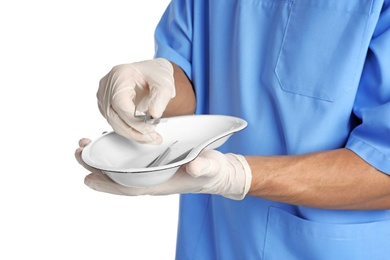 Male doctor holding dish with medical tools on white background, closeup. Medical objects
