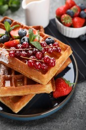 Delicious Belgian waffles with berries served on grey table