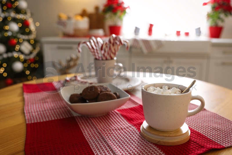 Delicious marshmallow cocoa on table in kitchen decorated for Christmas