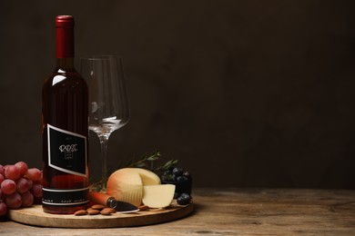 Photo of Bottle of red wine with glass and appetizers on wooden table. Space for text