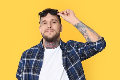 Photo of Portrait of handsome hipster man with stylish sunglasses on yellow background