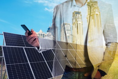 Double exposure of businessman with smartphone and solar panels installed outdoors. Alternative energy source